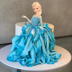 there is a cake that looks like a princess in a blue dress on the table