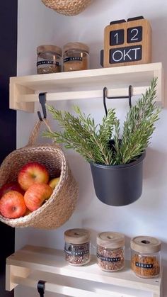 some apples are sitting in a basket on a shelf next to other jars and spices