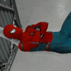 a man in red and blue jumpsuits is holding onto a metal fence with his hands