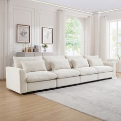 a living room filled with white furniture and large window covered in curtains on the windowsill