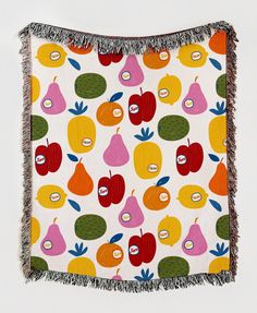 a blanket with fruit on it and fringes hanging from the side, in front of a white background