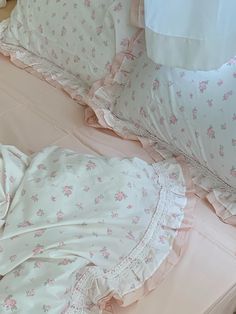 a bed with pink and white sheets and pillows on top of it, next to a pillow case