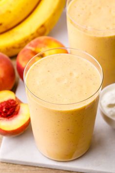 two glasses filled with smoothie next to sliced peaches