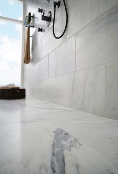 a bathroom with white marble counter tops and black faucet shower head mounted on the wall