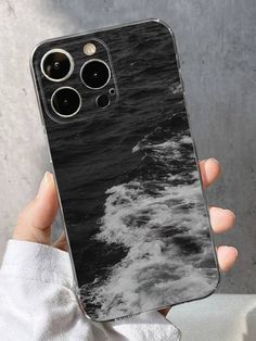 a person holding up an iphone case with the ocean in black and white on it