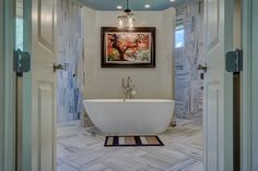 a bathroom with a bathtub, rug and framed painting on the wall above it