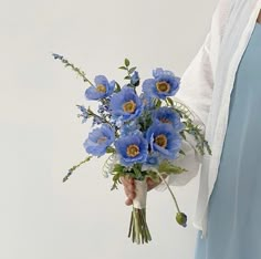 a woman holding a bouquet of blue flowers