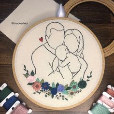 two hands are holding each other as they work on an embroidery project with scissors and thread