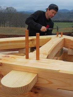 a man working on a wooden structure with a hammer in it's hand and another person standing next to him