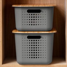 two plastic baskets sitting on top of a wooden shelf