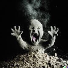 a creepy looking creature with its mouth open and hands in the air, surrounded by rocks