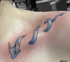 a woman's chest with two blue ribbon tattoos on her left shoulder and an arrow in the middle