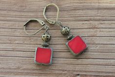 Red Earrings Dangle / Drop Earrings / Czech Glass Earrings / Gift for women / Gift for her Color : Opaque Red Picasso 10mm Square Czech Glass Beads. Finish : Antique brass tone findings. Size : Approx 1,5 inches including the antique Brass tone lever back. Ear wires : Antique brass tone lever back. Czech Glass Earrings : https://www.etsy.com/shop/NtikArtJewelry?ref=hdr_shop_menu&section_id=16062218 To visit my shop " NtikArtJewelry ": https://www.etsy.com/shop/NtikArtJewelry FREE DOMESTIC SHIPPI Red Brass Earrings With Ear Wire, Red Brass Dangle Jewelry, Red Brass Drop Earrings, Red Bohemian Rectangular Earrings, Bohemian Red Rectangular Earrings, Nickel-free Red Brass Earrings, Red Metal Drop Earrings, Red Metal Dangle Earrings, Nickel-free Red Drop Earrings