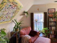 a living room filled with furniture next to a window covered in bookshelves and plants