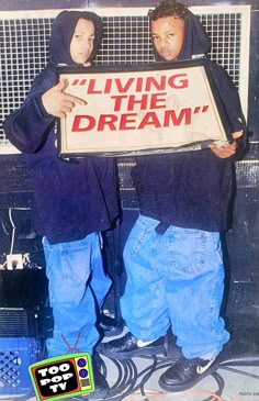 two young men holding a sign that says living the dream