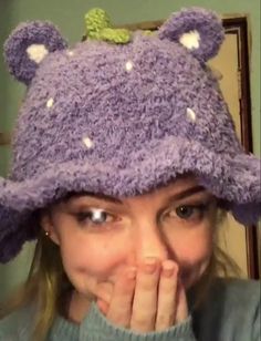 a woman wearing a purple bear hat with white dots on it's ears and nose