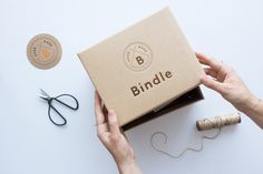 a box with the word bindle written on it next to some scissors and thread