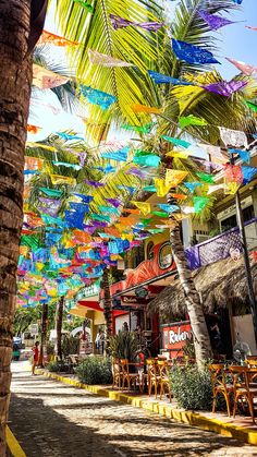 many colorful umbrellas are hanging from the ceiling in front of a cafe and restaurant