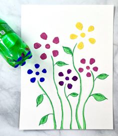 an art project with flowers painted on paper and a green water bottle next to it