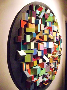 an art piece made out of colored blocks on a white wall next to a doorway