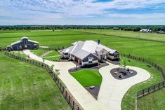 an aerial view of a large home in the middle of a green field with lots of grass