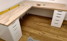 a white desk with drawers and a yellow ruler on the wall above it in a room