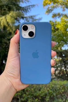 a person holding up an iphone case in front of the camera with trees in the background