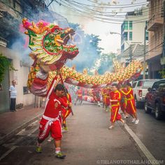 people in red and yellow outfits are walking down the street with dragon decorations on their head