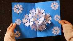 someone is making a snowflake out of paper