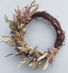 a wreath with dried flowers and twigs hanging on a wall