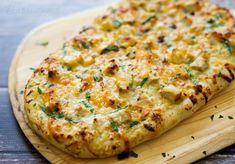 a cheesy pizza sitting on top of a wooden cutting board