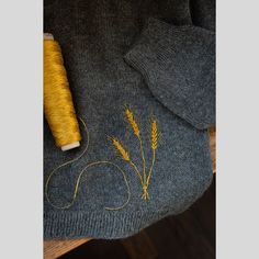 a yellow spool of thread sitting on top of a table next to a gray sweater