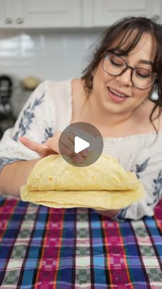 a woman is holding a tortilla in her hand and pointing to it on the table