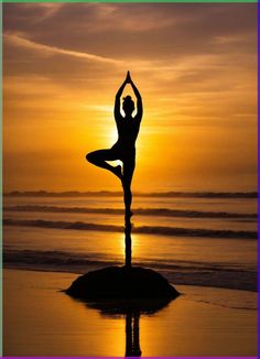 a woman doing yoga on the beach at sunset