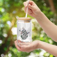 a person holding a glass jar with a straw in it