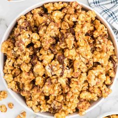 a white bowl filled with caramel popcorn on top of a marble counter next to other bowls