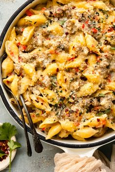 a pan filled with pasta covered in cheese and sauce next to some breadcrumbs