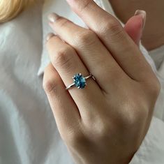 a woman's hand wearing a ring with a blue topazte on it