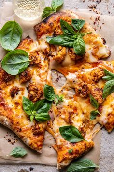 a pizza topped with cheese and spinach on top of a piece of parchment paper