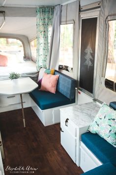 the inside of a camper with two couches and a table in front of it