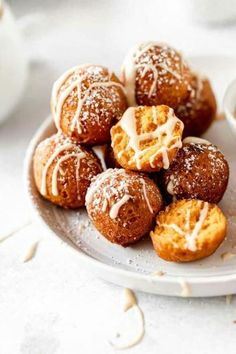 a white plate topped with donuts covered in powdered sugar and drizzled with icing