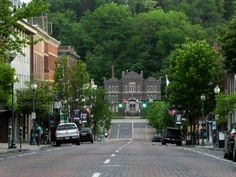 an empty street with cars parked on both sides and trees lining the road behind it