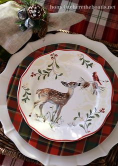 a plate with a deer on it sitting next to a christmas tree and plaid table cloth