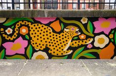 a painted mural on the side of a building with flowers and a cheetah