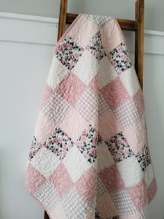 a pink and white checkered quilt hanging on a wooden chair next to a wall