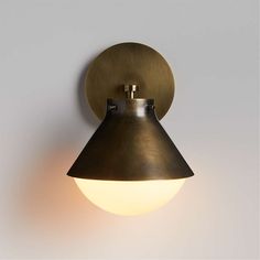 a light that is on the wall next to a white wall with a black and gold shade