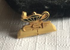 a gold brooch sitting on top of a black piece of cloth