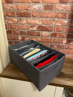 an open drawer with clothes in it next to a brick wall