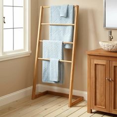 a towel rack in the corner of a bathroom with a sink and wooden flooring