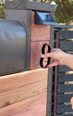 a person is opening the door to a mailbox that has been made from wood